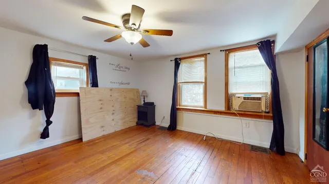 a view of an empty room with a window and wooden floor