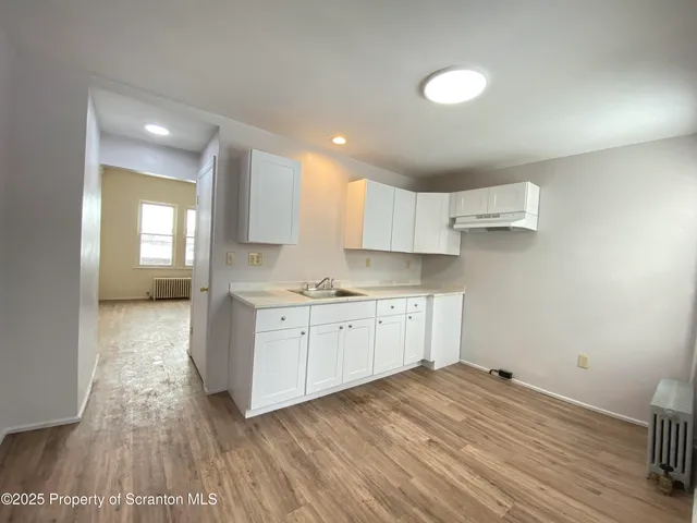 an empty room with wooden floor and entrance