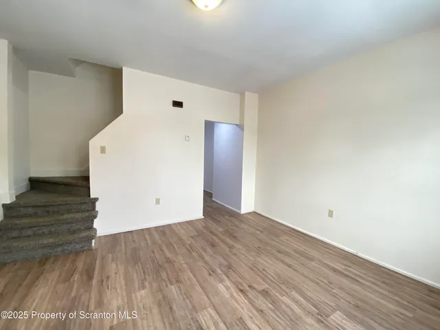 an empty room with wooden floor and entrance