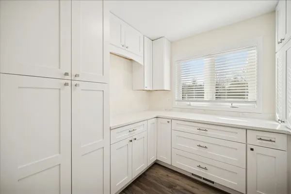 a kitchen with white cabinets and window