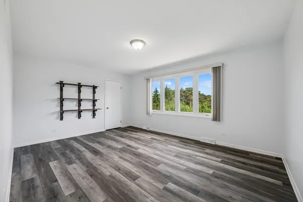 a view of an empty room with window and mirror