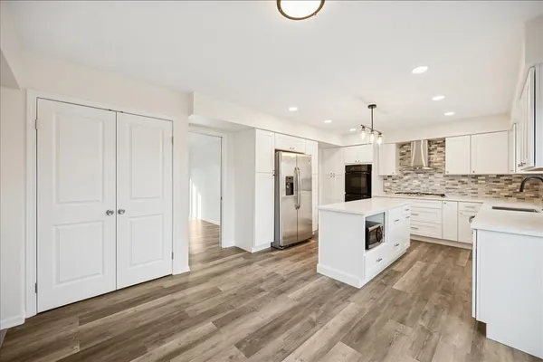 a large white kitchen with white cabinets and stainless steel appliances