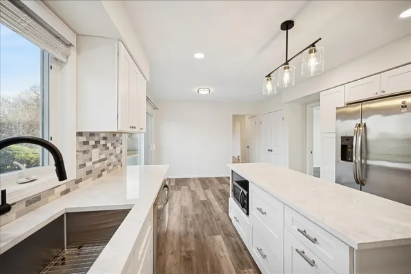 a large kitchen with a large counter top a sink stainless steel appliances and cabinets