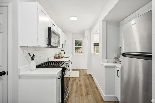 662 29th Street Ogden, UT 84403 - Photo 5 of 23 Contemporary kitchen featuring white cabinetry, subway tile backsplash, stone-finish countertops, stainless steel appliances, and wood-finish flooring
