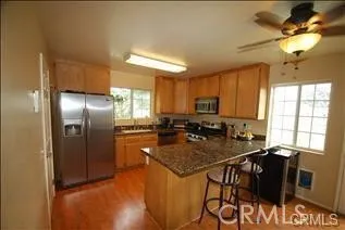 a kitchen with stainless steel appliances granite countertop a stove a refrigerator a sink a dining table and chairs with wooden floor