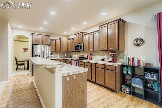 a open kitchen with stainless steel appliances granite countertop a stove top oven a sink dishwasher and a microwave with wooden floor