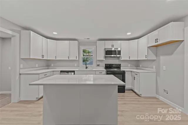 a kitchen with a sink a stove a refrigerator and white cabinets