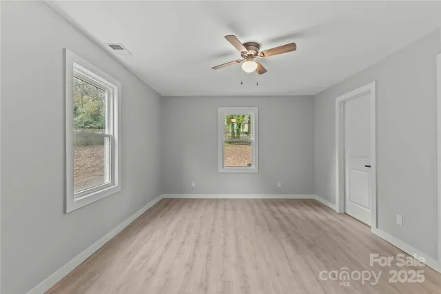 a view of an empty room with a window and wooden floor