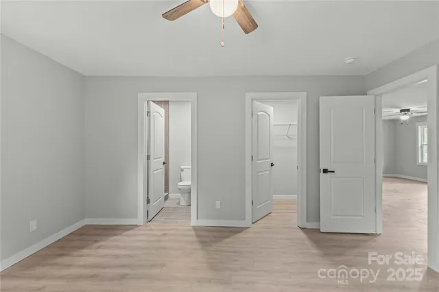 an empty room with closet and a chandelier fan