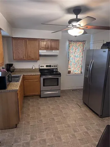 a kitchen with stainless steel appliances granite countertop a sink a stove a refrigerator cabinets and a window