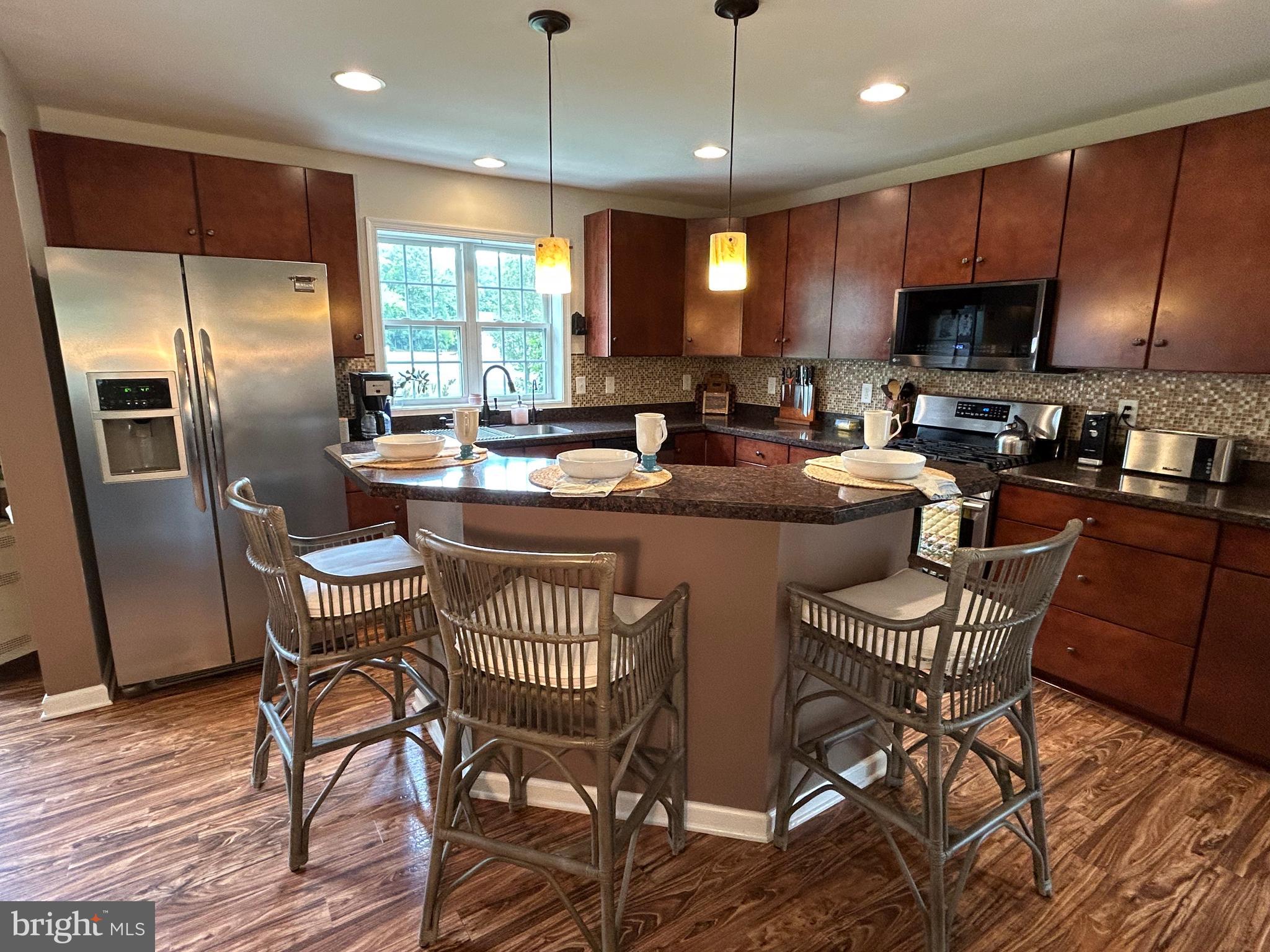 20346 Cool Spring Road Milton, DE 19968 - Photo 24 of 67 a kitchen with stainless steel appliances granite countertop a stove a refrigerator a sink a dining table and chairs with wooden floor