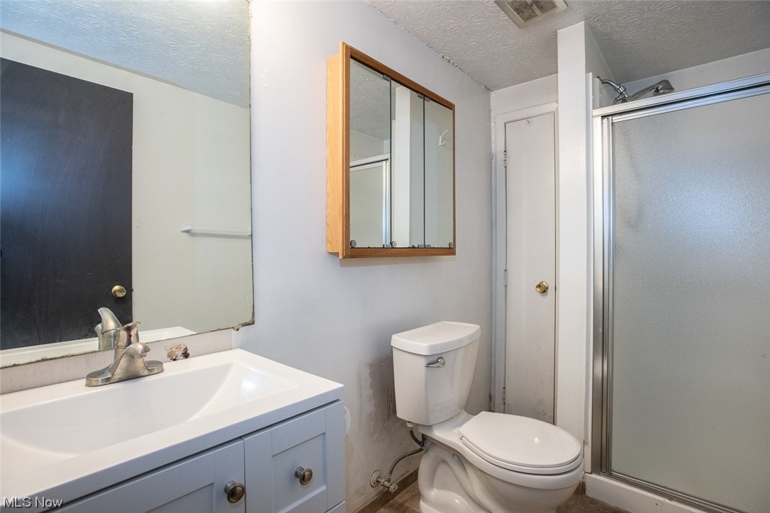 14358 Prospect Road Strongsville, OH 44149 - Photo 26 of 35 Bathroom with a textured ceiling, toilet, a shower with door, and oversized vanity