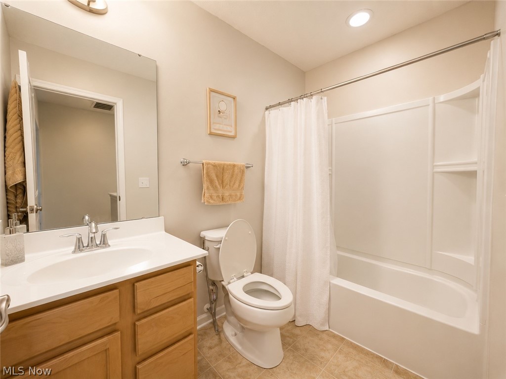 867 Starr Ridge Street Southeast Massillon, OH 44646 - Photo 21 of 29 Bathroom featuring a wood-finish vanity with a white countertop, chrome fixtures, a full-width mirror, a toilet, and a white tub/shower combination with integrated shelving