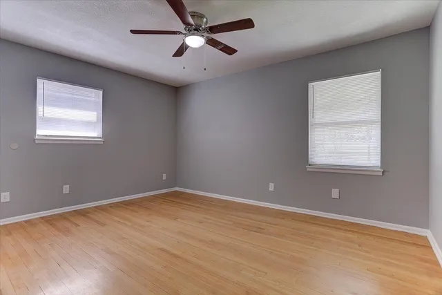an empty room with wooden floor and windows