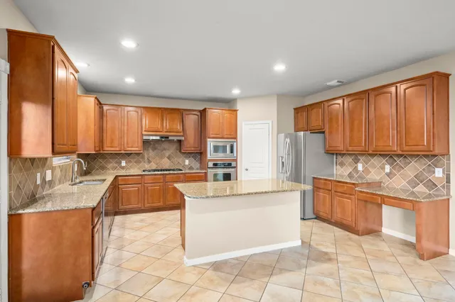 a large kitchen with stainless steel appliances granite countertop a stove a sink and a microwave