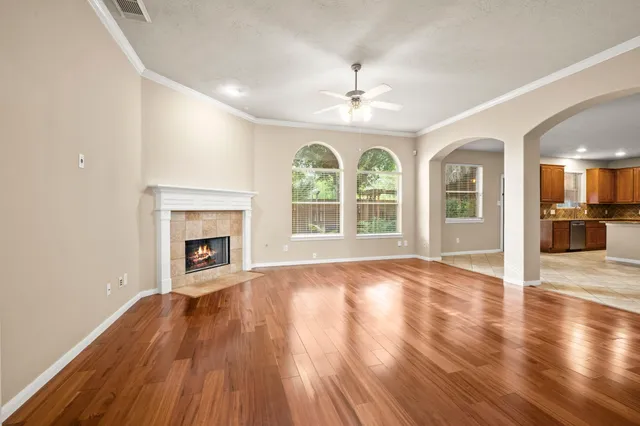 an empty room with wooden floor fireplace and windows
