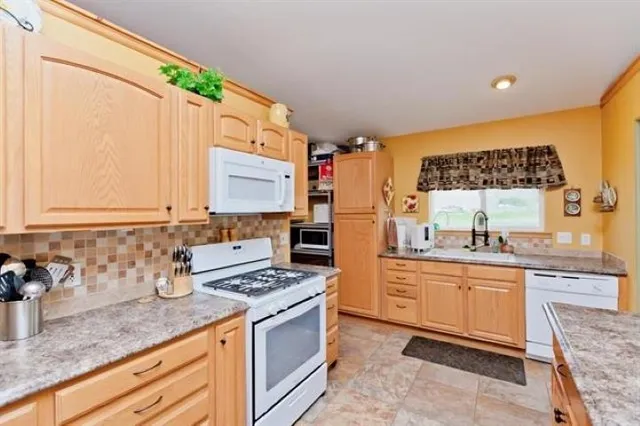a large kitchen with kitchen island granite countertop a sink and white cabinets