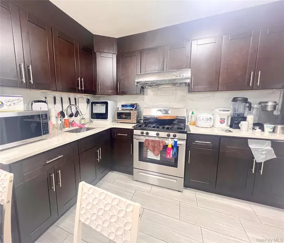 a kitchen with kitchen island granite countertop stainless steel appliances wooden cabinets sink and stove