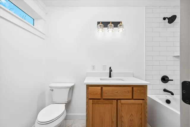 a bathroom with a granite countertop sink a toilet and mirror