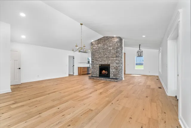 a view of an empty room with wooden floor and a fireplace