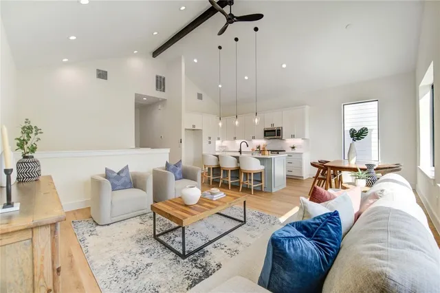 a living room with furniture kitchen view and a wooden floor
