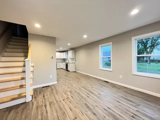 a view of empty room with wooden floor and window