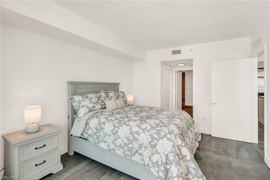 3000 Oasis Grand Boulevard, Unit 606 Fort Myers, FL 33916 - Photo 19 of 47 a bedroom with a bed and a lamp on dresser