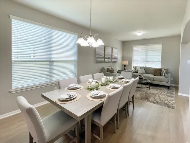 a view of a dining room and livingroom with furniture wooden floor and a chandelier
