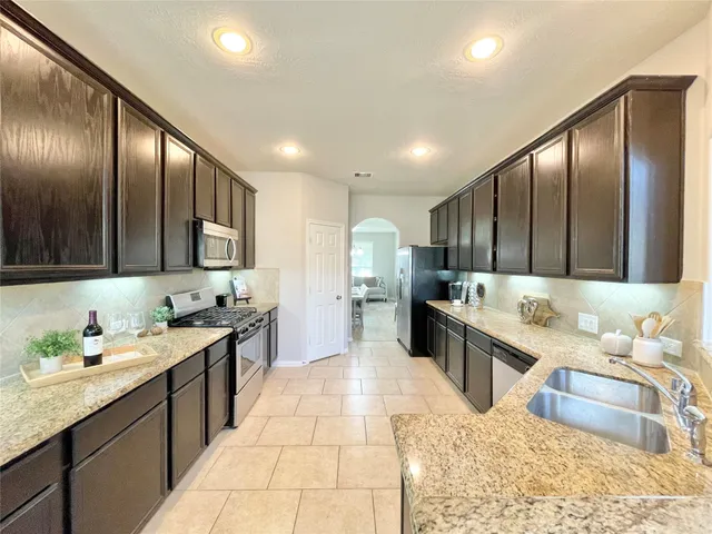 a large kitchen with a large counter top sink and stainless steel appliances