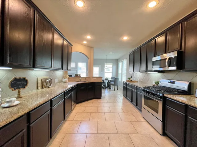 a kitchen with stainless steel appliances granite countertop a sink a stove top oven and cabinets