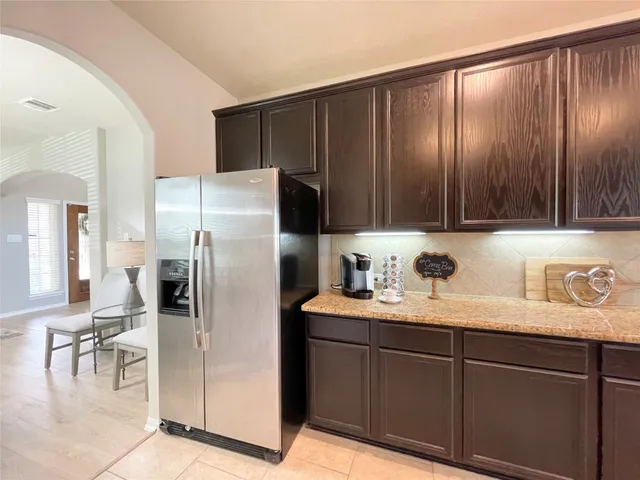 a kitchen with stainless steel appliances granite countertop a refrigerator a sink and wooden cabinets
