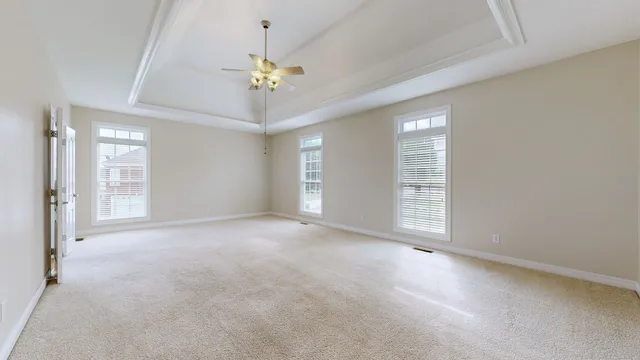 an empty room with a chandelier fan and window