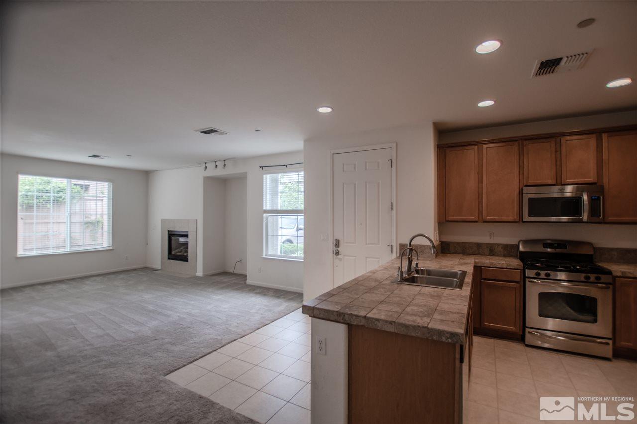 1900 Wind Ranch Road, Unit RENO Reno, NV 89521 - Photo 7 of 25 a kitchen with kitchen island granite countertop a stove sink and microwave