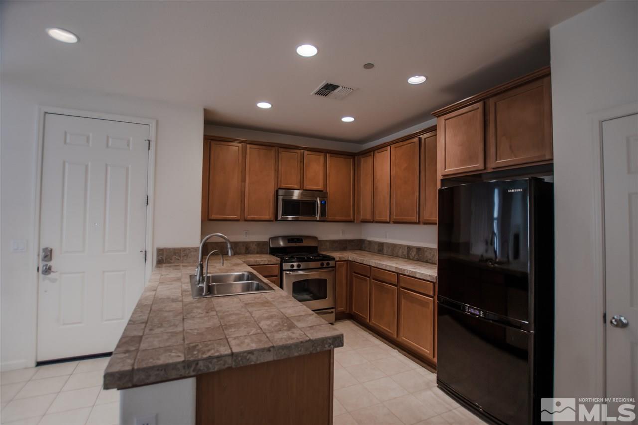 1900 Wind Ranch Road, Unit RENO Reno, NV 89521 - Photo 8 of 25 a kitchen with kitchen island granite countertop stainless steel appliances sink stove refrigerator and cabinets