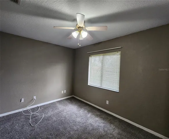 an empty room with a window and a fan