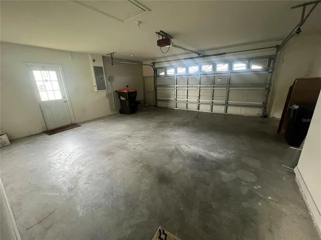 a view of a pool with lawn chairs plants and large tree