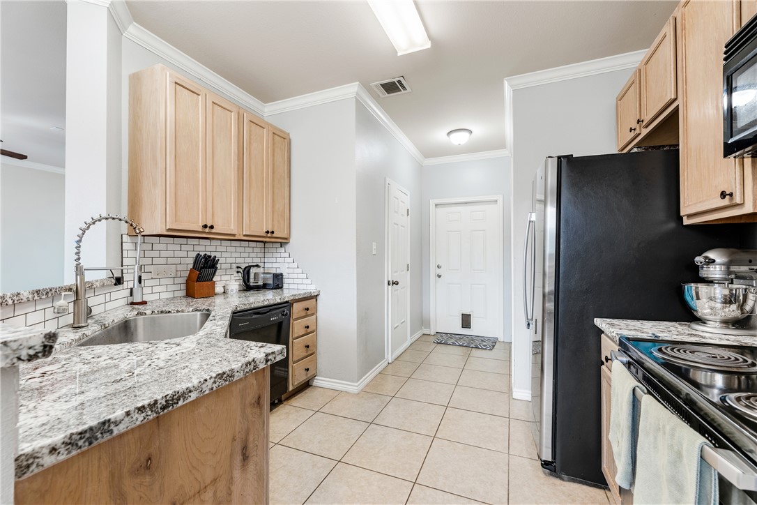 1425 West Villa Maria Road, Unit 1004 Bryan, TX 77801 - Photo 9 of 23 a kitchen with granite countertop a refrigerator stove and sink