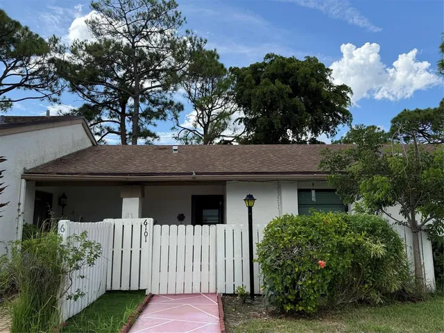 a view of a house with a small yard plants and large trees