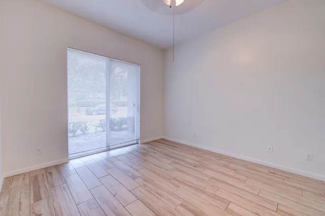 an empty room with wooden floor and windows