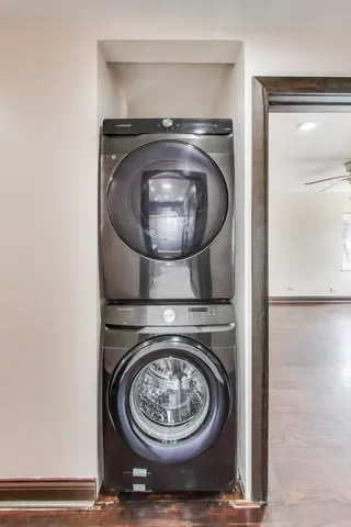 an empty room with wooden floor chandelier fan and windows