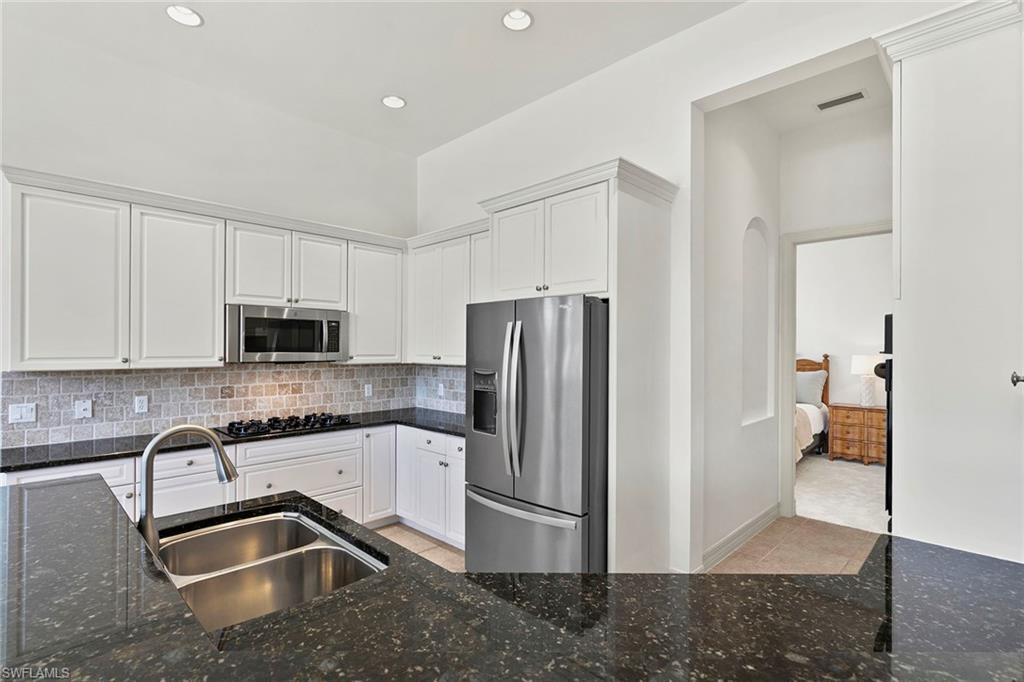17005 Porta Vecchio Way, Unit 102 Naples, FL 34110 - Photo 9 of 50 a kitchen with granite countertop a refrigerator and a sink