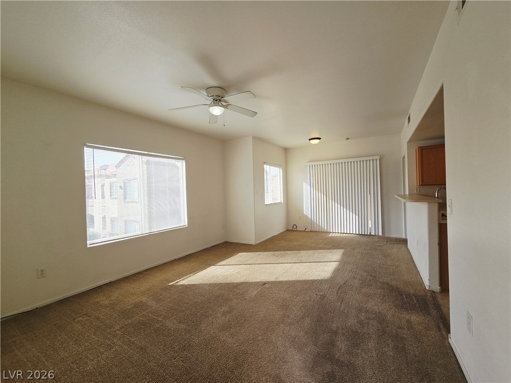 9580 West Reno Avenue, Unit 283 Las Vegas, NV 89148 - Photo 5 of 19 Unfurnished living room with ceiling fan, healthy amount of natural light, and dark colored carpet