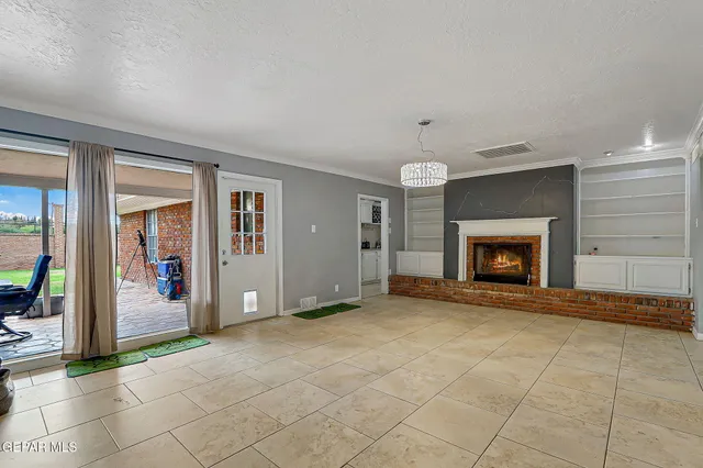 an empty room with a fireplace and chandelier fan