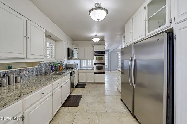 a kitchen with granite countertop a refrigerator sink and cabinets
