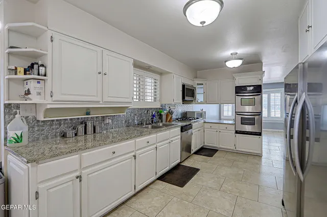 a kitchen with white cabinets and window