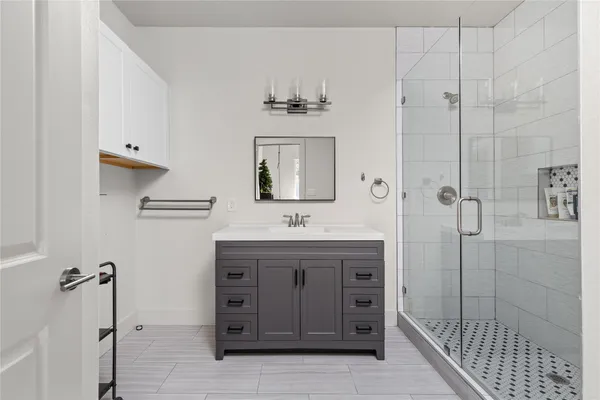 a bathroom with a granite countertop sink a mirror and shower