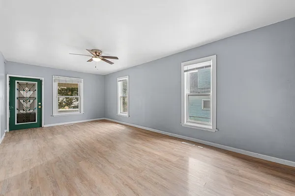 a view of an empty room with a window and wooden floor