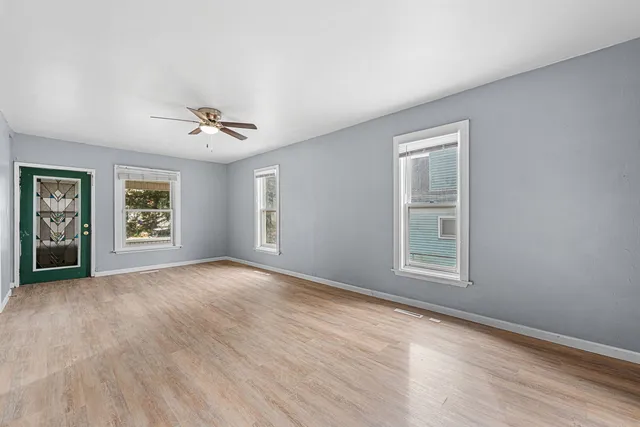 a view of an empty room with a window and wooden floor
