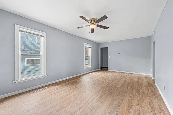 a view of empty room with wooden floor and fan