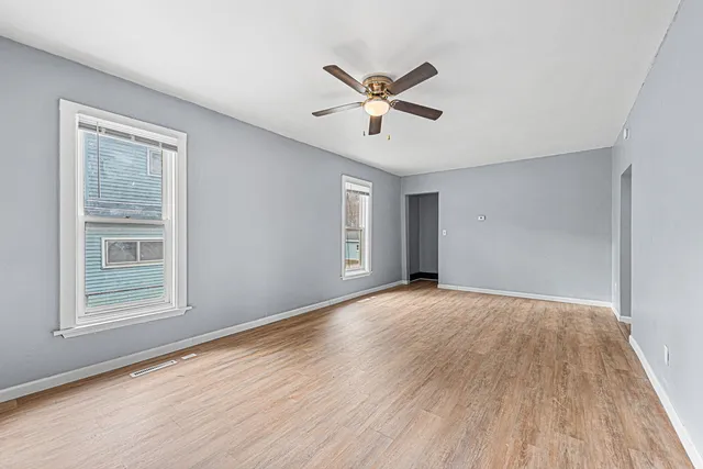 a view of empty room with wooden floor and fan
